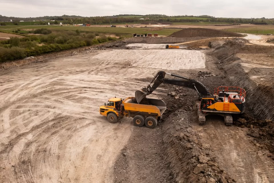 Aerial view of brownfield area with digger loading a dump truck.